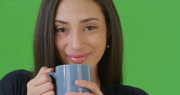 A close-up portrait of a Hispanic woman drinking coffee on green screen