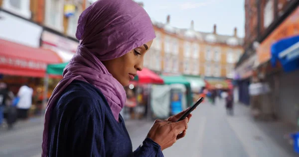 Young Muslim woman in London England using the phone in Brixton London UK