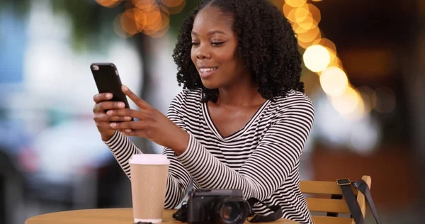 Sonriente Mujer Negra Sienta Mesa Café Aire Libre Mirando Teléfono — Foto de Stock