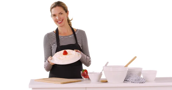 Cheerful Caucasian woman presenting cake tasting frosting with finger