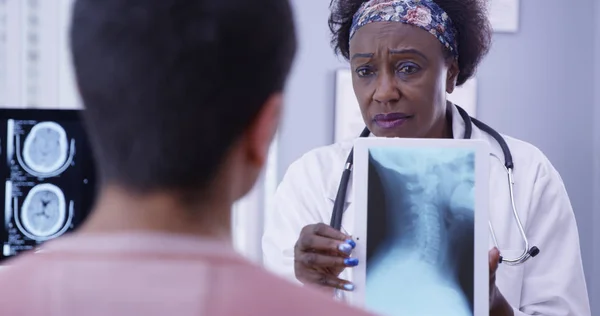 资深黑人医生用电子笔记本片显示颈部 — 图库照片
