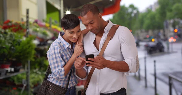 城市中的年轻黑人夫妇在人行道上观看外面的智能手机 — 图库照片