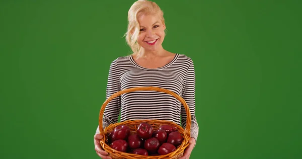 緑色の画面上の有機の赤いリンゴのバスケットを保持している陽気な白人女性 — ストック写真