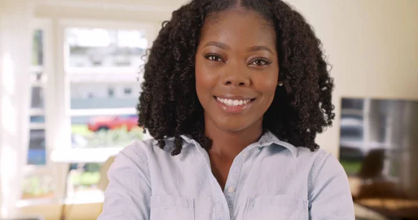Close up attractive black woman standing in living room smiling at camera