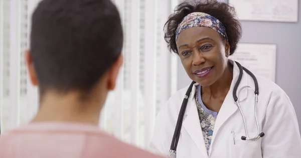 积极的非洲女医生在医疗办公室内与男性患者交谈 — 图库照片