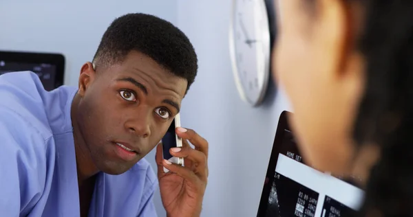 在使用智能手机时与女同事交谈的非裔美国人医生的亲密接触 — 图库照片