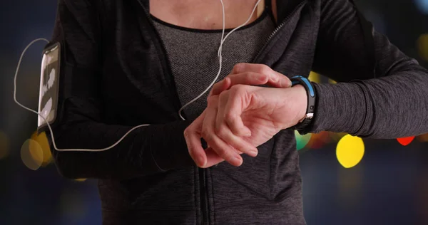 Close up of mature female runner using smartwatch
