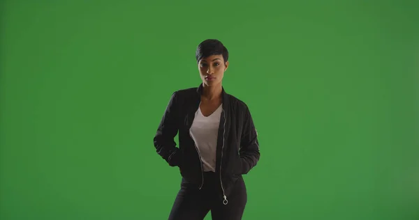坚强时尚的黑人女性摆姿势与手在她的口袋在绿色屏幕上 — 图库照片