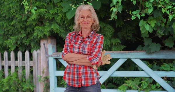 Mature woman in red flannel shirt takes a break from working on the farm