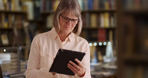 Okouzlující Starší Žena Pomocí Kapesní Tablet Zařízení Nastavení Knihovny — Stock fotografie