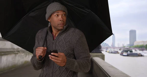 Retrato Hombre Negro Con Paraguas Guardando Teléfono Día Agitado Inglaterra — Foto de Stock