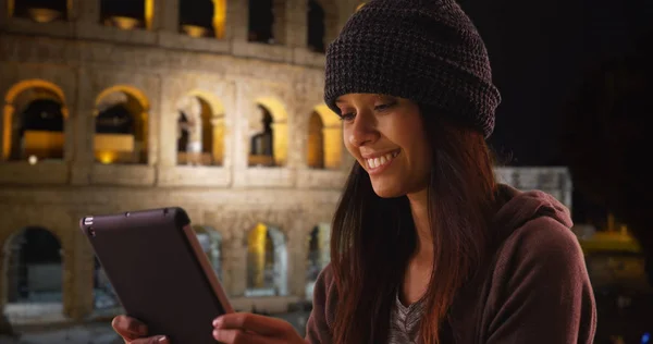 Tourist woman using tablet computer in front of Coliseum at night