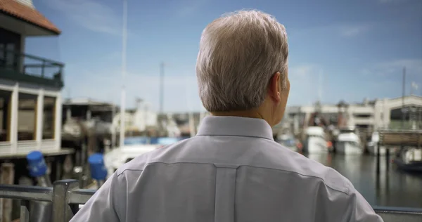 Portrait of mature white man standing on seaport looking at sailboats