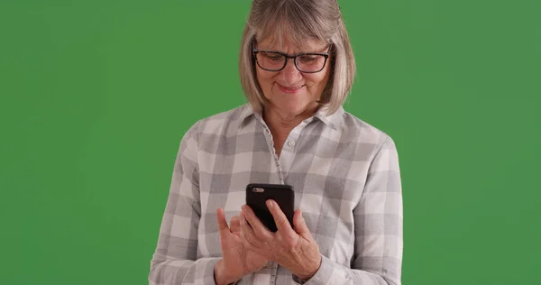 迷人的老白人妇女在智能手机上发短信在绿色屏幕上 — 图库照片