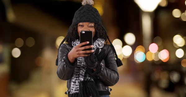 Cute black woman in urban setting talking to camera taking selfie with mobile