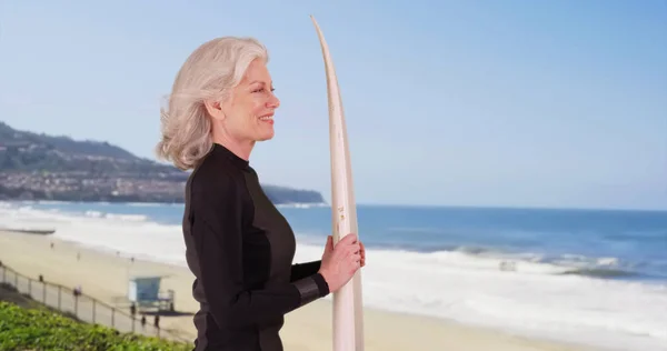 Rijpe Vrouw Wetsuit Holding Surfplank Oceaan Terwijl Het Strand Kijken — Stockfoto