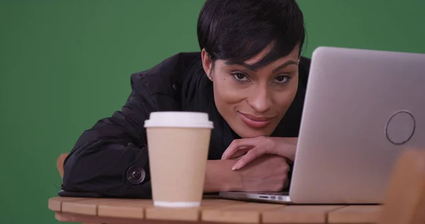 Black woman with laptop resting head on cafe table on green screen