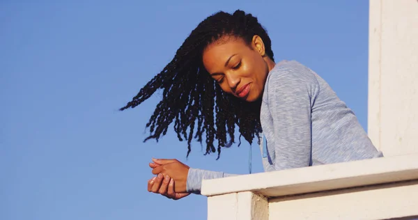 Happy black woman leaning on rail smiling