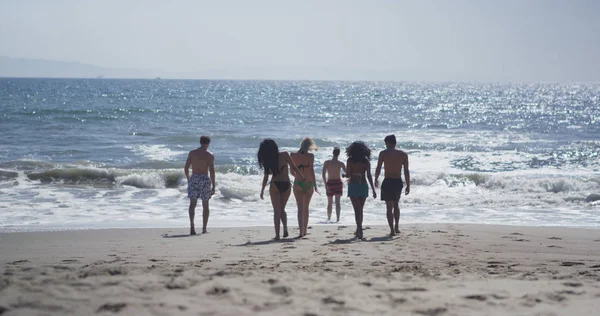 Young hipster group of interracial friends wandering the beach