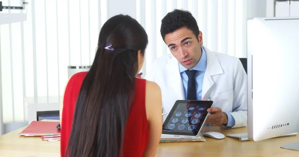 Médico Hispânico Revisando Raios Cerebrais Com Paciente Mesa — Fotografia de Stock