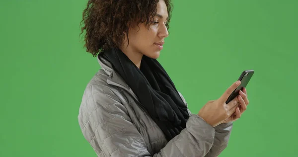 Young African American millennial woman uses her phone on green screen