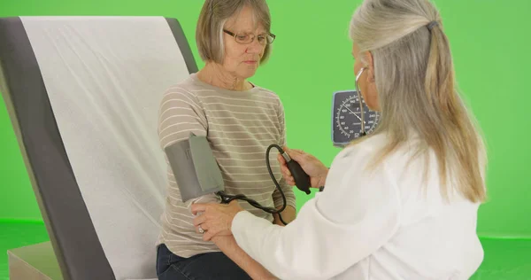 高齢患者は 彼女の血圧は 緑色の画面に彼女の医師がチェックを取得します — ストック写真