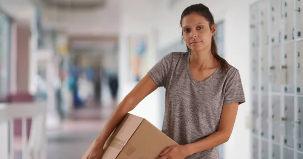 Serious young woman in post office carrying box for shipping