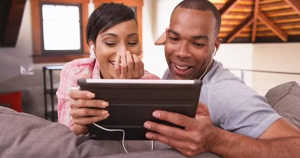 A black couple watches a video on their tablet