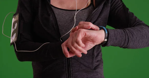 Closeup of woman jogger checking watch in sportswear on green screen