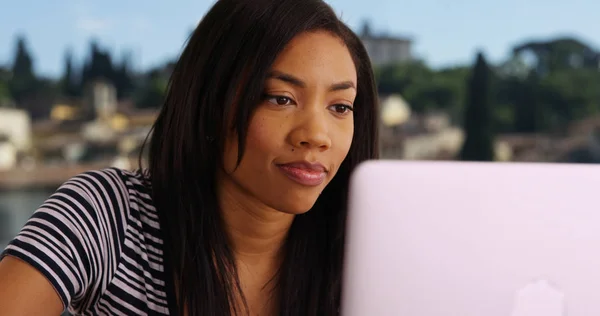Close up of black woman on vacation in Rome working on laptop