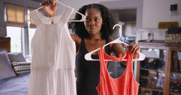 Portrait of attractive black woman deciding what dress to wear
