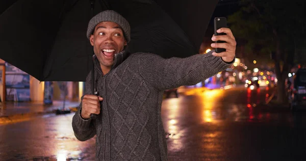 An African American man takes a selfie in the rain