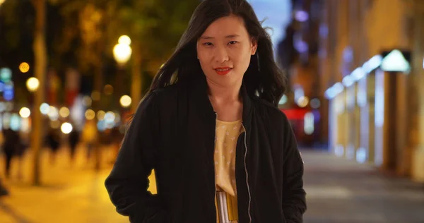 晚上站在城市街道上的中国女子身穿黑色轰炸机夹克 — 图库照片