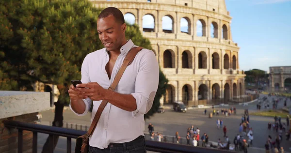 African-American male on vacation in Rome sends text near Colosseum