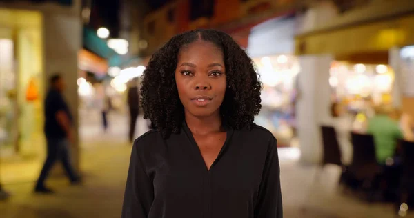 Portrait of black woman standing on small street in Venice busy with nightlife