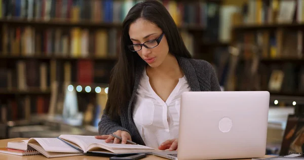 Latina college student works on laptop at the library