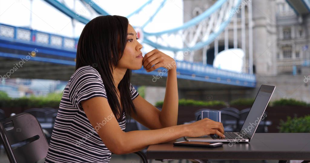 Black woman on vacation in London answering work emails on laptop