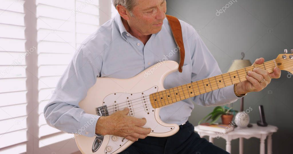Portrait of senior male guitarist playing guitar