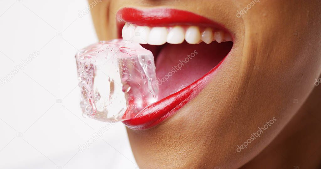 Close up of woman holding ice in mouth on white background