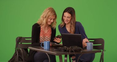 Güzel kadınlar Cafe telefon ve dizüstü bilgisayar üzerinde yeşil ekran kullanarak gülüyorsun çifti