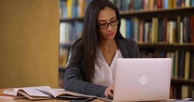 Gözlüklü İspanyol kadın bir deneme sınıfı için bilgisayarda yazıyor.