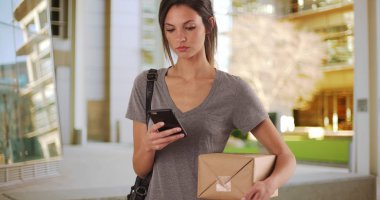 Bin yıllık erkek modern bina dışında paketin izini sürmek için smartphone app kullanarak