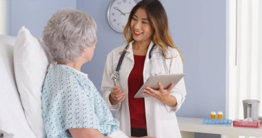 Japon doktor hastane yatağında yaşlı hasta ile konuşma