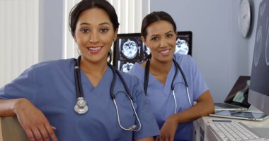 Bilgisayar başında oturan Latin ve Afro-Amerikan doktorlar portresi