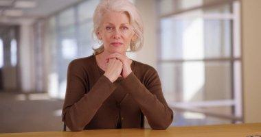 Ciddi Olgun kadın profesyonel kamera ofis ortamında staring at arıyorsunuz