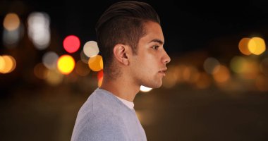 Arka planda ışık ve sokak ile gece ayakta duran genç milenyum adamı yan görünümü