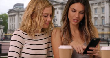 İki arkadaş smartphone Buckingham Palace yakınındaki Londra'da paylaşımı görünümü Kapat