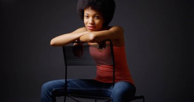 Raslantı ile silah üzerinde sandalye arkasında oturan Afrika kadın