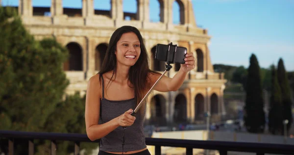 可爱的黑发旅行女孩在罗马体育馆前使用自拍棒 — 图库照片