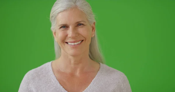 一位年长的女人站在绿色的屏幕上微笑着 — 图库照片